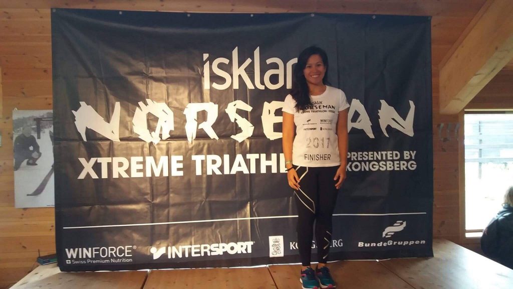 Laarni Paredes taking a photo in front of the Norseman Xtreme Triathlon backdrop