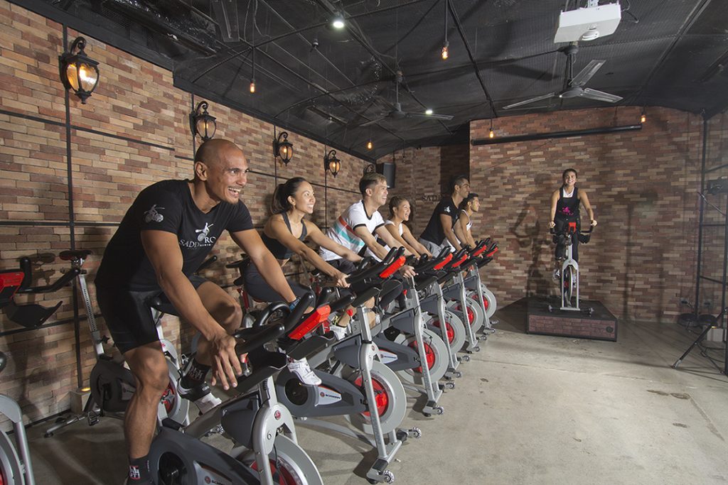 An indoor cycling class incorporates moves that work out from head to toe