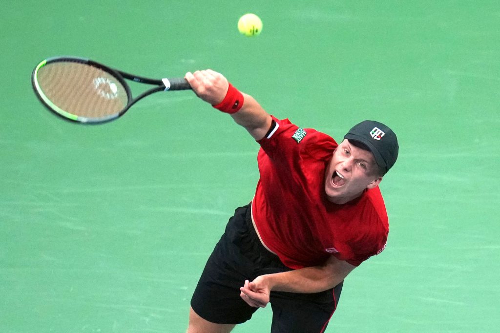 Jenson Brooksby of the United States serves to Novak Djokovic