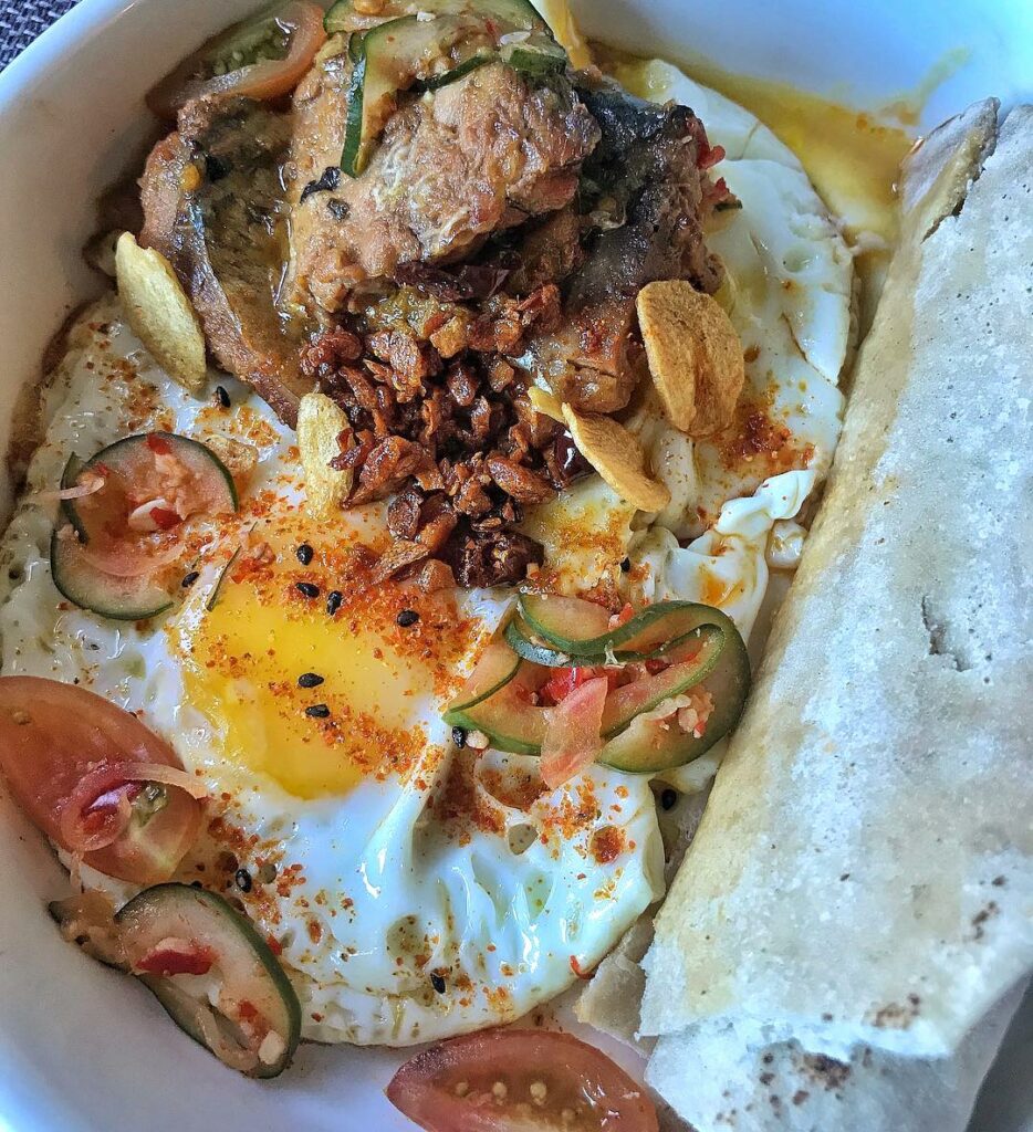 JP Anglo's brunch bowl: Sunny side up chili garlic spicy eggs with curried sardines, pickled cucumbers, and onions and served with whole wheat pita bread
