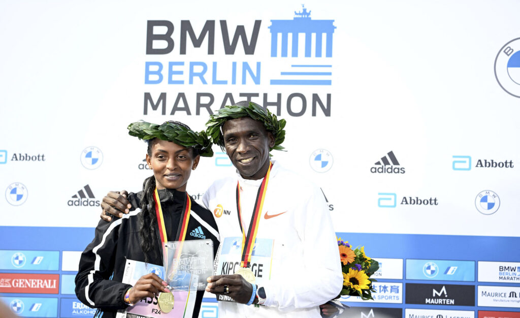 Race champions Ethiopia's Tigist Assefa and Kenya's Eliud Kipchoge pose on the podium after the Berlin Marathon