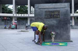 Marcio Pereira da Silva, known as Pele, a street artist, lays down a Brazilian flag in front of Maracana Stadium as people mourn the death of Brazilian soccer legend Pele, in Rio De Janeiro, Brazil