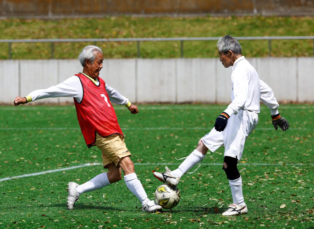 Red Star’s midfielder Mutsuhiko Nomura (left), 83, shoots to score a goal against Blue Hawai’s goalkeeper Hiroshi Nishino, 87,