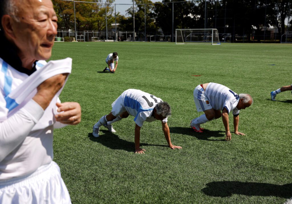 Nihon Soccer OB Club members, a team whose members’ average age is 77.4-year-old, do physical training before a practice match in Tokyo