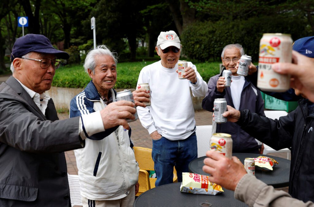 Red Star’s midfielder Mutsuhiko Nomura, 83, and his teammates toast with canned beers at a park