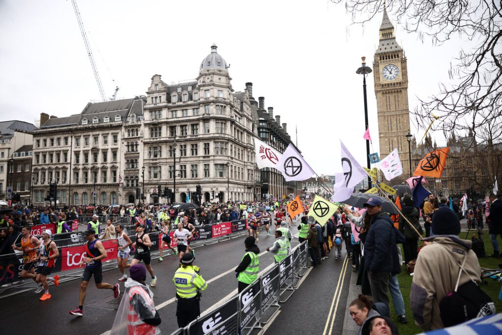 Participants run past the Houses of Parliament and Extinction Rebellion protesters during the London Marathon
