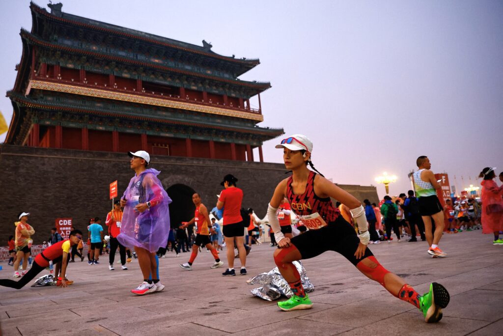 Participants stretch to warm up before the Beijing Marathon